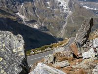 a motorcycle on a scenic mountain road with a rock in front of it and a valley below