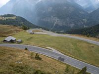 a street curve winding through a beautiful mountainous area with mountains in the background and low clouds in the sky