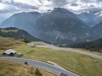 a street curve winding through a beautiful mountainous area with mountains in the background and low clouds in the sky