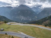 a street curve winding through a beautiful mountainous area with mountains in the background and low clouds in the sky