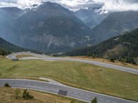 a street curve winding through a beautiful mountainous area with mountains in the background and low clouds in the sky