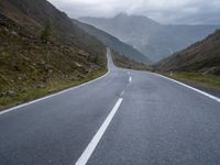 an empty highway running up the side of a mountain slope under stormy skies and clouds