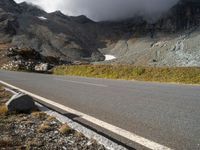 the mountains are towering above a lone highway, with a snow covered hill below it