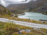 this is an image of a view of the mountains, lake and a roadway in the foreground