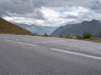 a motorcycle riding along a winding street near mountains on cloudy day or day while on mountain