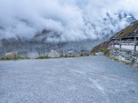 the motorcycle is sitting in a gravel lot on a mountain side with mist in the sky above