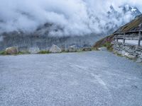 the motorcycle is sitting in a gravel lot on a mountain side with mist in the sky above