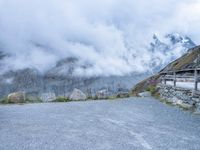 the motorcycle is sitting in a gravel lot on a mountain side with mist in the sky above