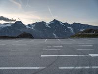 an empty parking lot with mountains in the background and a road in the foreground