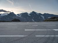 an empty parking lot with mountains in the background and a road in the foreground