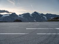 an empty parking lot with mountains in the background and a road in the foreground