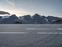 an empty parking lot with mountains in the background and a road in the foreground