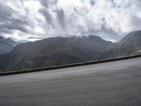 a highway with mountains in the background and the clouds are low in the sky above it