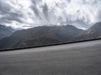 a highway with mountains in the background and the clouds are low in the sky above it