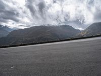 a highway with mountains in the background and the clouds are low in the sky above it