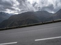 a highway with mountains in the background and the clouds are low in the sky above it