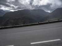 a highway with mountains in the background and the clouds are low in the sky above it