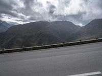 a highway with mountains in the background and the clouds are low in the sky above it