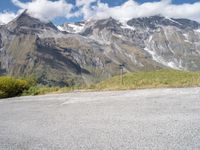 a red motorcycle is sitting on the road beside some mountains and trees, with snow capped peaks in the background