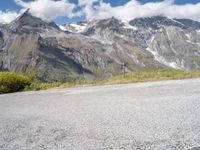 a red motorcycle is sitting on the road beside some mountains and trees, with snow capped peaks in the background