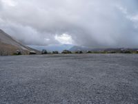 an empty parking lot with the mountains in the background with lots of clouds in the sky