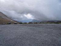 an empty parking lot with the mountains in the background with lots of clouds in the sky