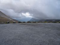 an empty parking lot with the mountains in the background with lots of clouds in the sky