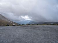 an empty parking lot with the mountains in the background with lots of clouds in the sky