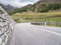 a winding road with stones and fences on both sides of it leading down to a mountain pass