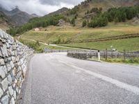 a winding road with stones and fences on both sides of it leading down to a mountain pass