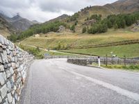 a winding road with stones and fences on both sides of it leading down to a mountain pass