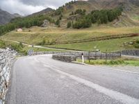 a winding road with stones and fences on both sides of it leading down to a mountain pass