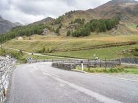 a winding road with stones and fences on both sides of it leading down to a mountain pass