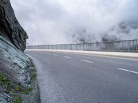 a road with rocks on either side and mountain in the background with mists over it