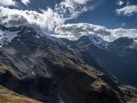 a couple of people are standing on the top of a mountain with some mountain peaks in the distance