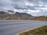 a mountain pass on a cloudy day with no cars on it, as the road winds through