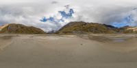 a panoramic view of a mountain range and beach area with sand dunes in front