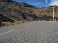 the long, empty road leads into a valley filled with mountains and rocks along the side