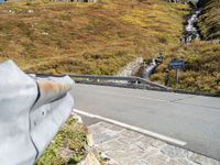 a hand over an object on the side of a road near the street and mountains