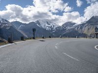 a person is riding their skateboard on the road in front of some mountains with snow