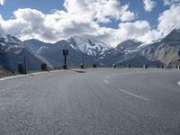 a person is riding their skateboard on the road in front of some mountains with snow