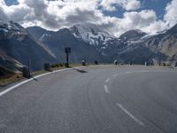 a person is riding their skateboard on the road in front of some mountains with snow