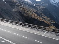 two road markings on the side of a mountain next to a highway with a fence