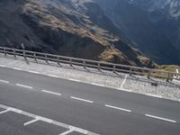 two road markings on the side of a mountain next to a highway with a fence