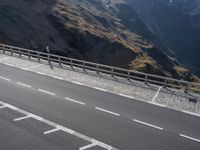 two road markings on the side of a mountain next to a highway with a fence