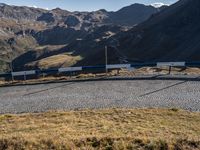 there is a large curve in the mountain with mountains behind it, some blue and white lines around a small patch in grass