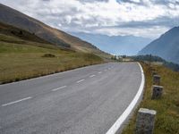 an empty highway stretches along the mountains in switzerland at high altitudes, near a bench next to a road sign