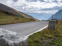 an empty highway stretches along the mountains in switzerland at high altitudes, near a bench next to a road sign