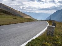 an empty highway stretches along the mountains in switzerland at high altitudes, near a bench next to a road sign