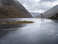 road sign next to empty street, in the mountains, with rain clouds covering the background